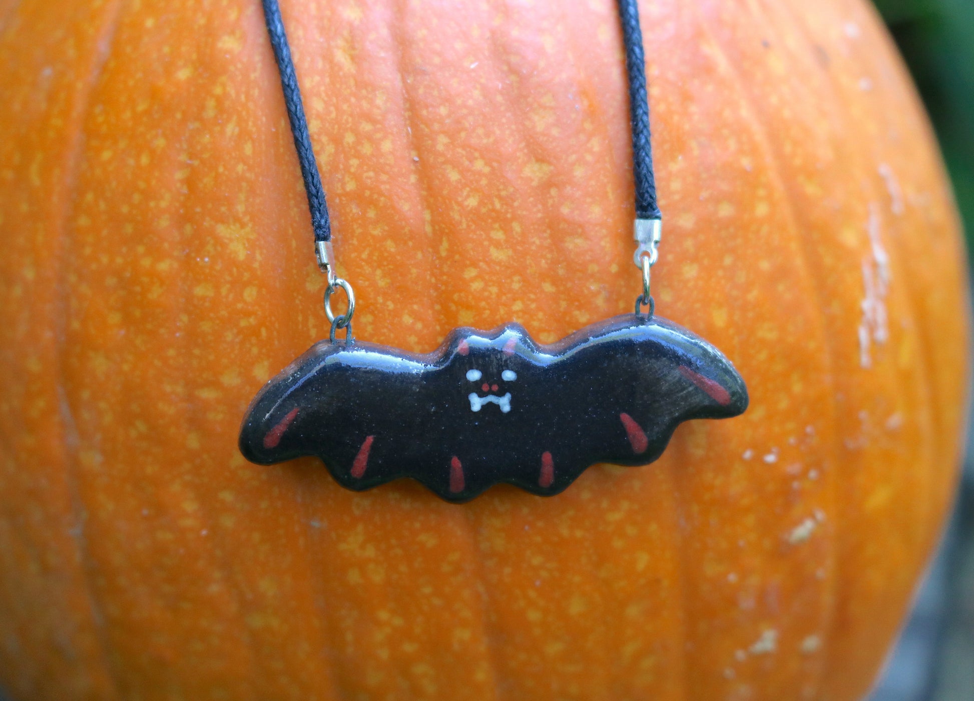 Bat Necklace in red color-way shown on a pumpkin